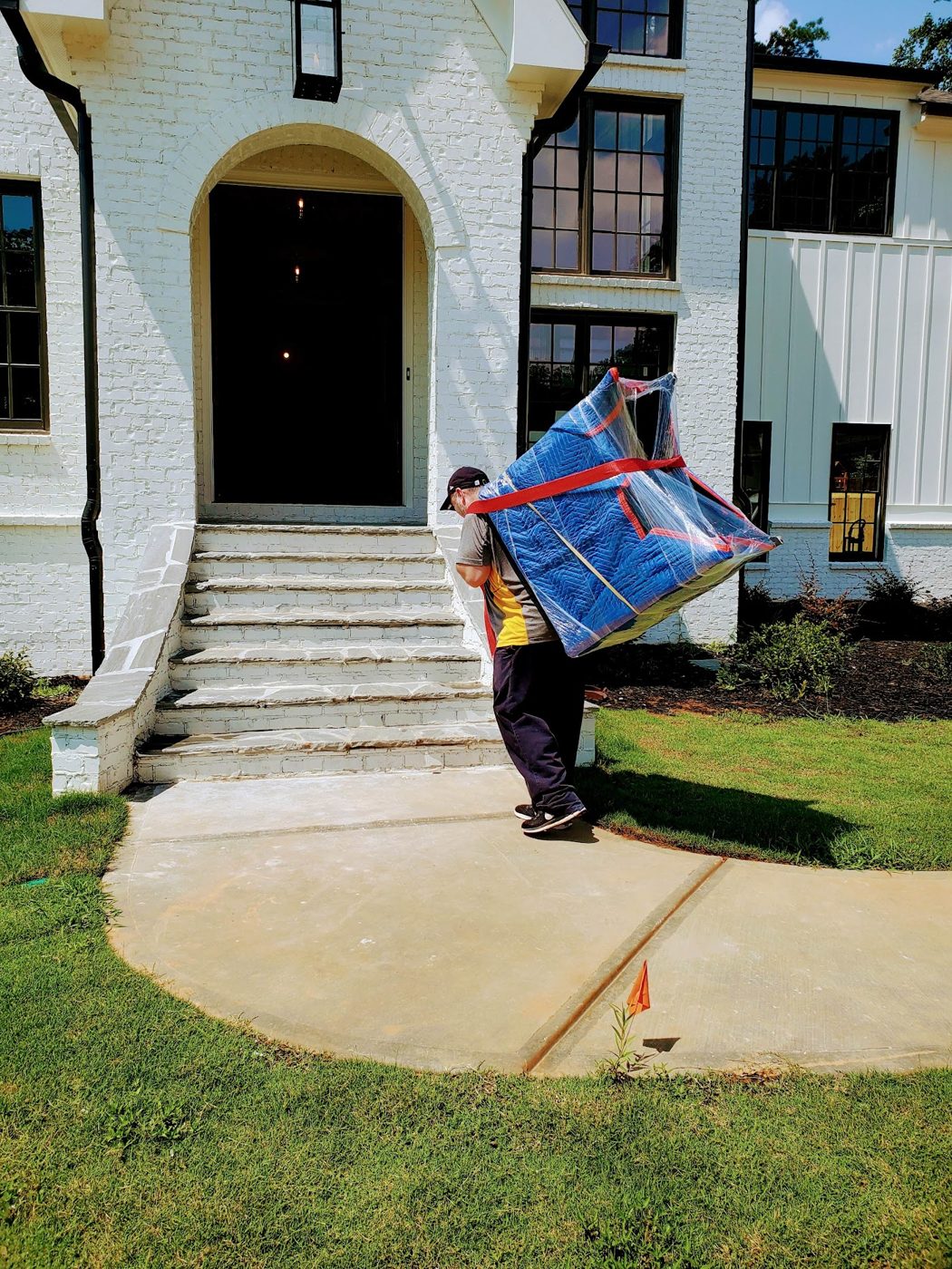 Mover carrying a wrapped item into a house